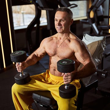 gladsome gentleman with bare torso exercising at the gym