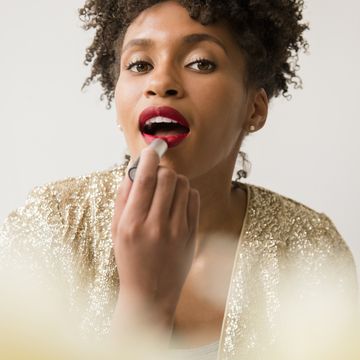 glamorous black woman applying red lipstick