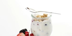 glass and spoon with muesli, yoghurt, berries, red currants, blueberries, strawberry, blackberry