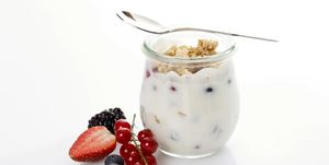 glass and spoon with muesli, yoghurt, berries, red currants, blueberries, strawberry, blackberry