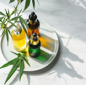 glass bottles with cbd oil, thc tincture and hemp leaves on a marble background flat lay cosmetics cannabis oil