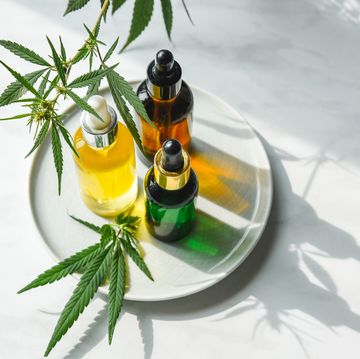glass bottles with cbd oil, thc tincture and hemp leaves on a marble background flat lay cosmetics cannabis oil