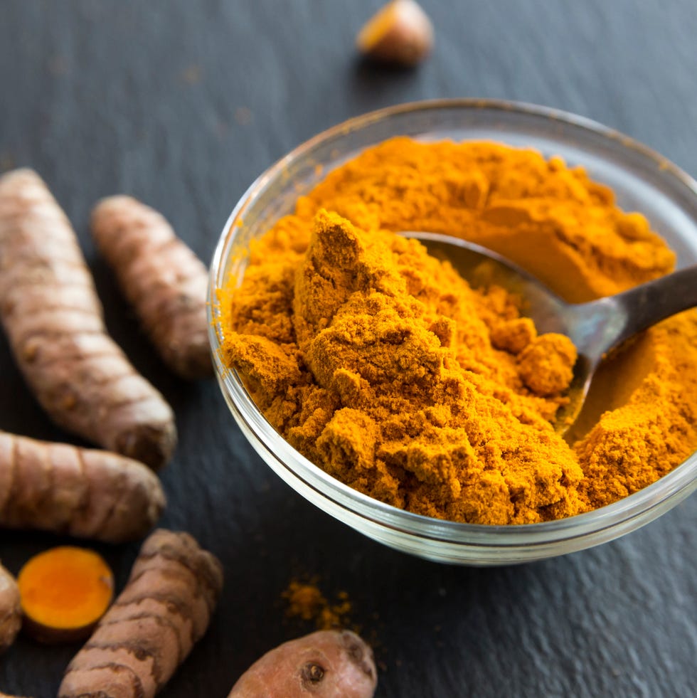 Glass bowl of curcuma powder and fresh organic curcuma on slate glass bowl of curcuma powder and fresh organic curcuma on slate