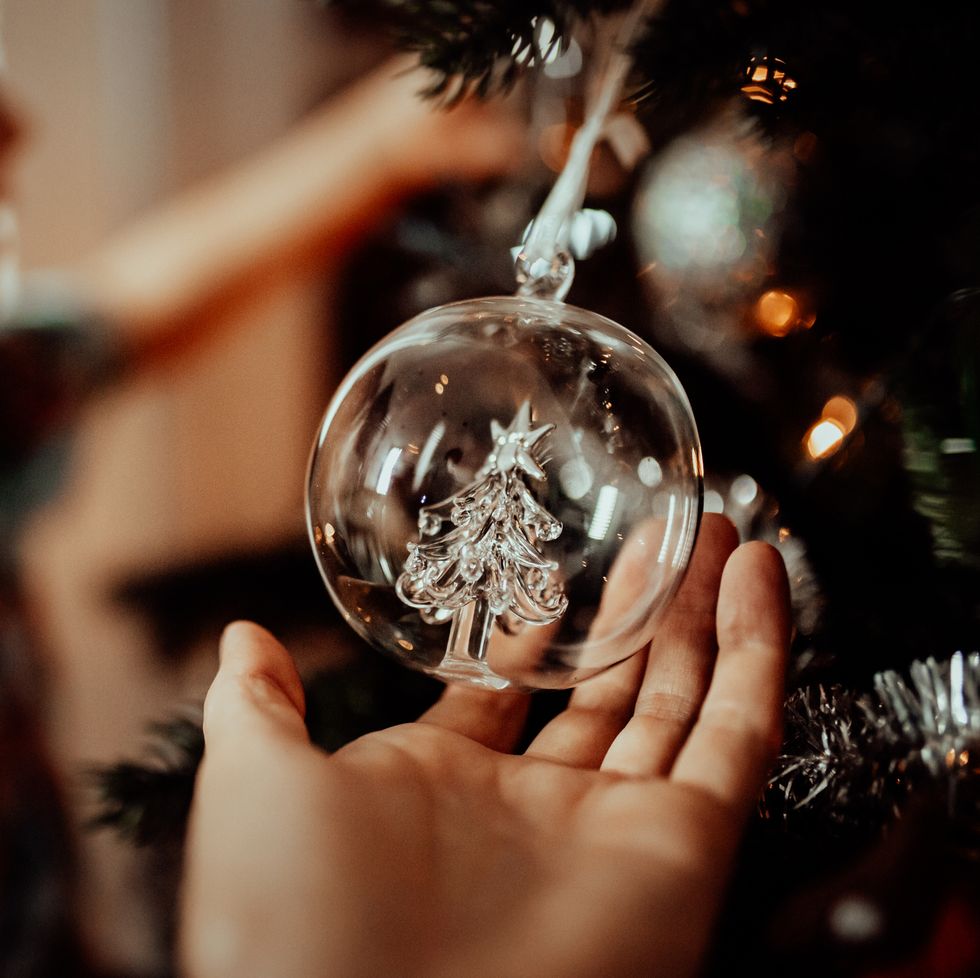 little girl admires the christmas tree ornaments with mum