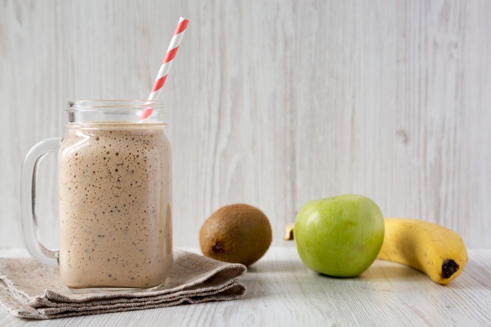 glass jar mug filled with banana, kiwi, apple smoothie, side view close up