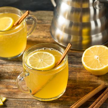 hot toddy in glass mug with lemon slices and cinnamon sticks