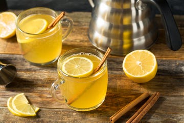 hot toddy in glass mug with lemon slices and cinnamon sticks