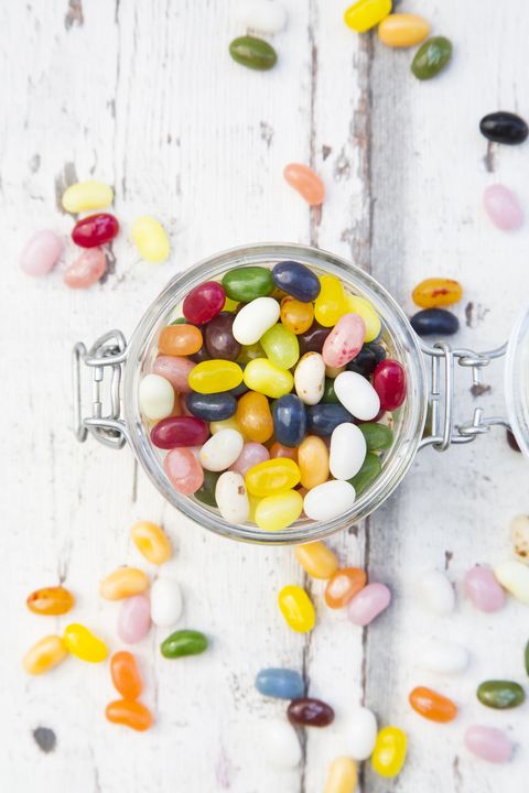 glass of colourful sweet jellybeans on white wood