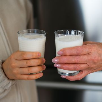 glass of fruit kefir and ayran in hands of a kid ad his grandmother.