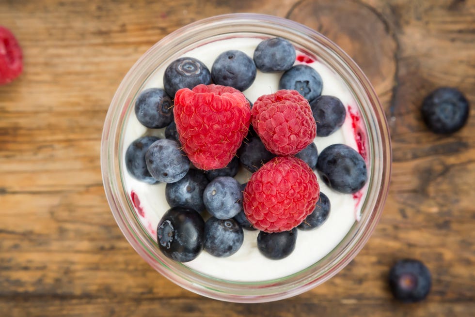 Glass of Greek yogurt with breey gorats, fresh blueberries and raspberries, close-up