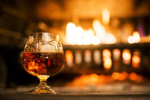 glass of hard liquor in front of the fireplace night