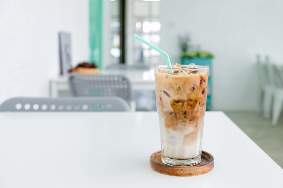 a glass of ice coffee on the white table in coffee shop