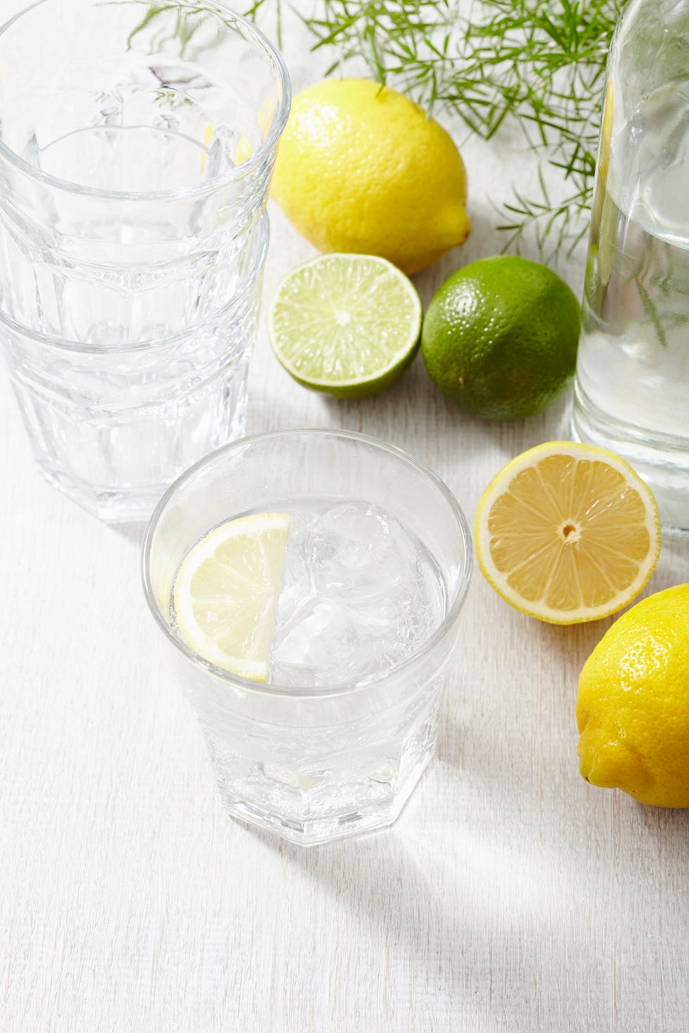 a glass of iced water with lemons and limes