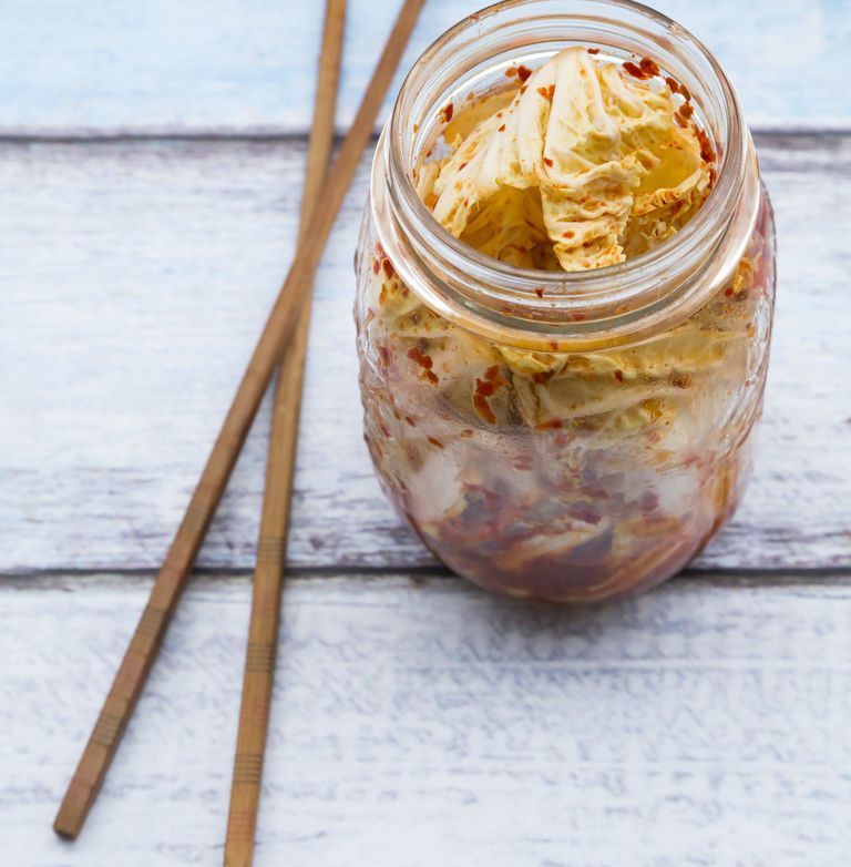 Glass of Kimchi and chopsticks on wood