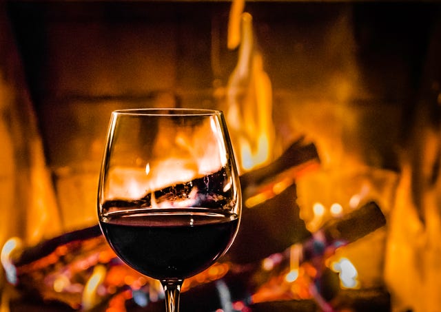 A glass of red wine standing in front of the fireplace. Close up