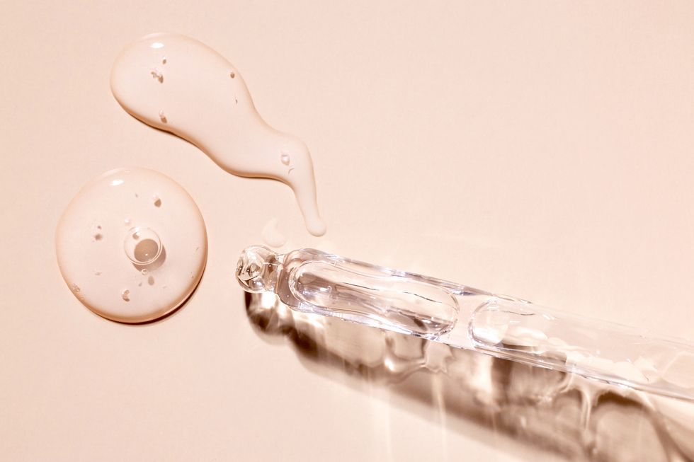 glass pipettes with drops of transparent serum on a beige background, skin care cosmetics concept