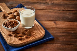 glass with almond milk on rustic wooden table with copy space