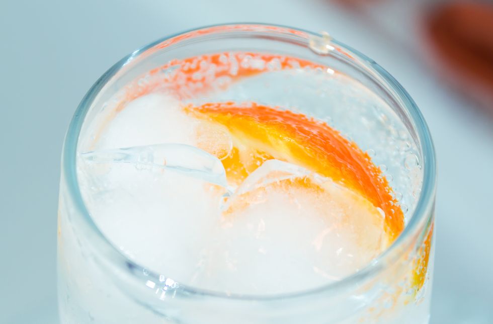 glass with oranges, ice, sparkling water close up