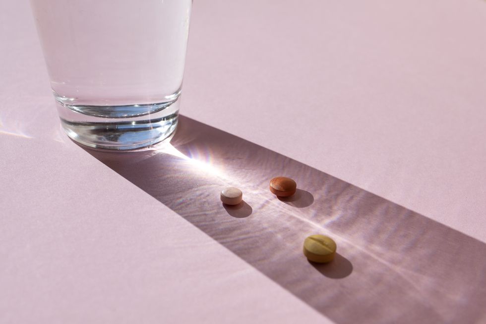 glass with pills on the pink background