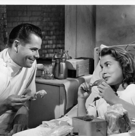 glenn ford sitting beside nancy davis while she lays in bed as they both eat a drumstick of chicken in a scene from the film 'the doctor and the girl', 1949. (photo by metro goldwyn mayer/getty images)