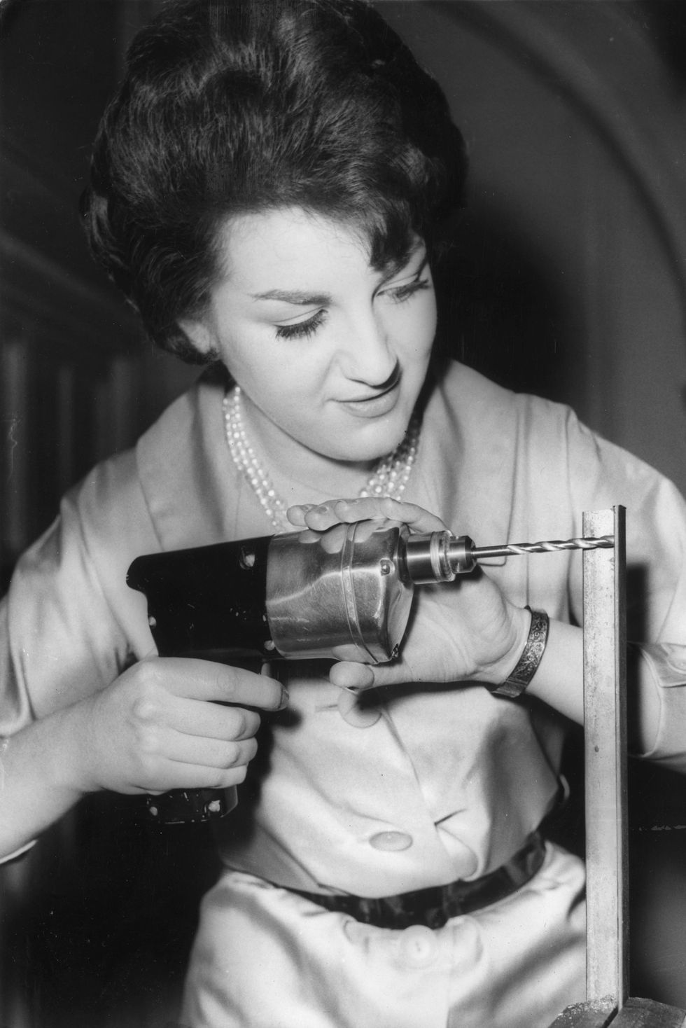 a woman holding an early model of a cordless power drill