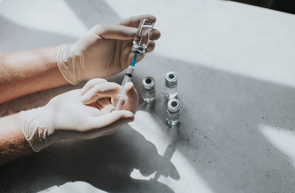 gloved hand holds a syringe and a phial   conceptual medical image with space for copy