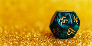 glowing green divination dice aquarius on gold colored background