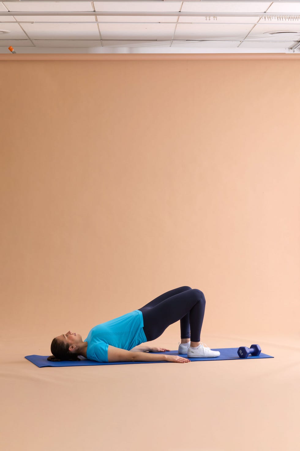 woman performs ab exercises on a blue mat