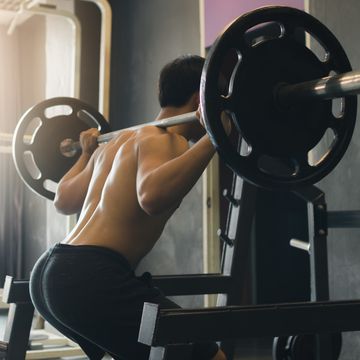 Midsection Of Man Squatting In Gym