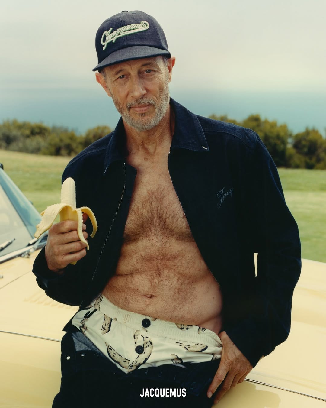 person holding a banana while posing next to a car