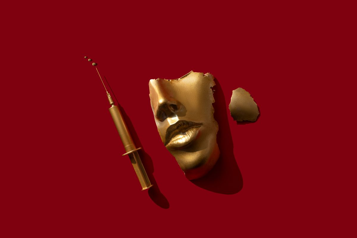 gold colored syringe and face mask on the red background