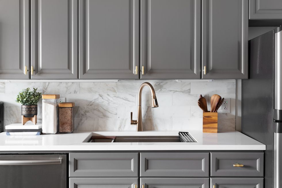 a gold kitchen faucet detail with grey cabinets.