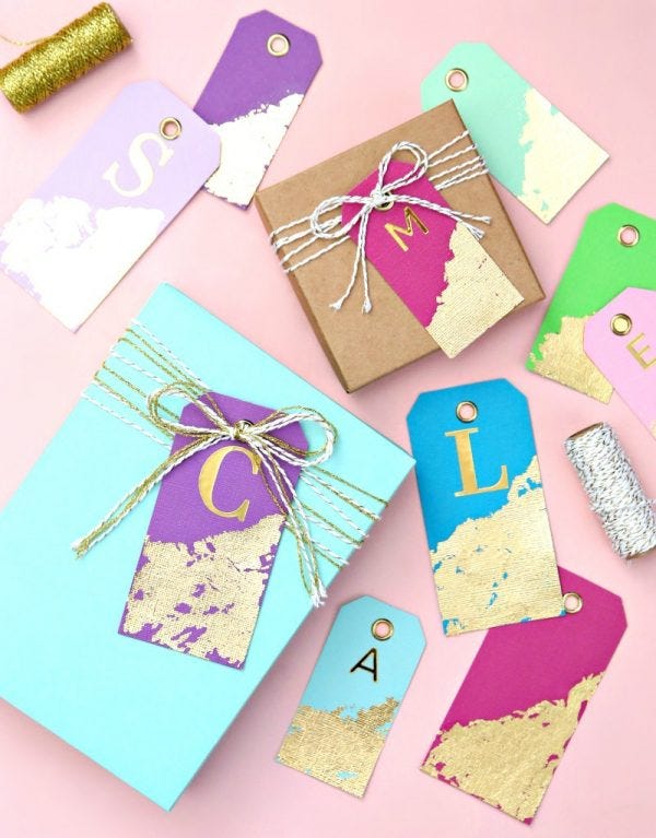 a collection of gift boxes and tags arranged on a pastel pink background