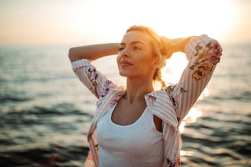 young woman enjoying sunset by the sea