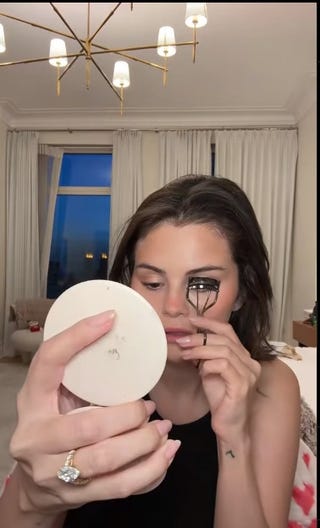 person applying makeup while looking into a handheld mirror