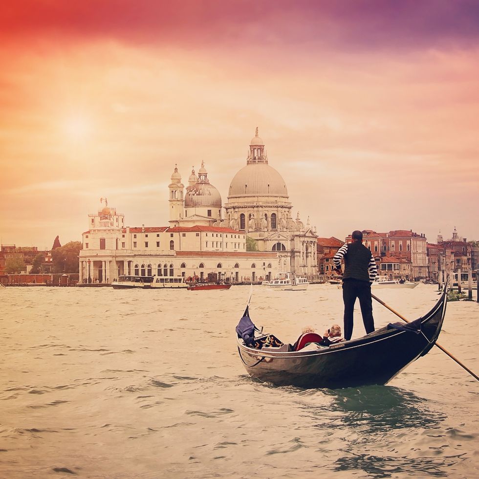 gondolier with tourists on the grand canal and santa maria della salute , venice, italy