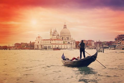 gondolier with tourists on the grand canal and santa maria della salute , venice, italy