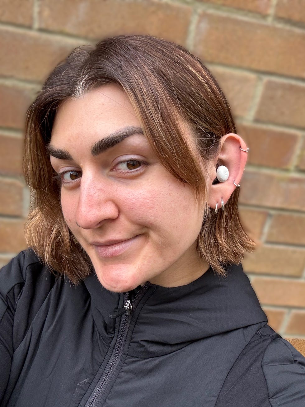 woman taking a selfie wearing a white google pixel bud pro 2