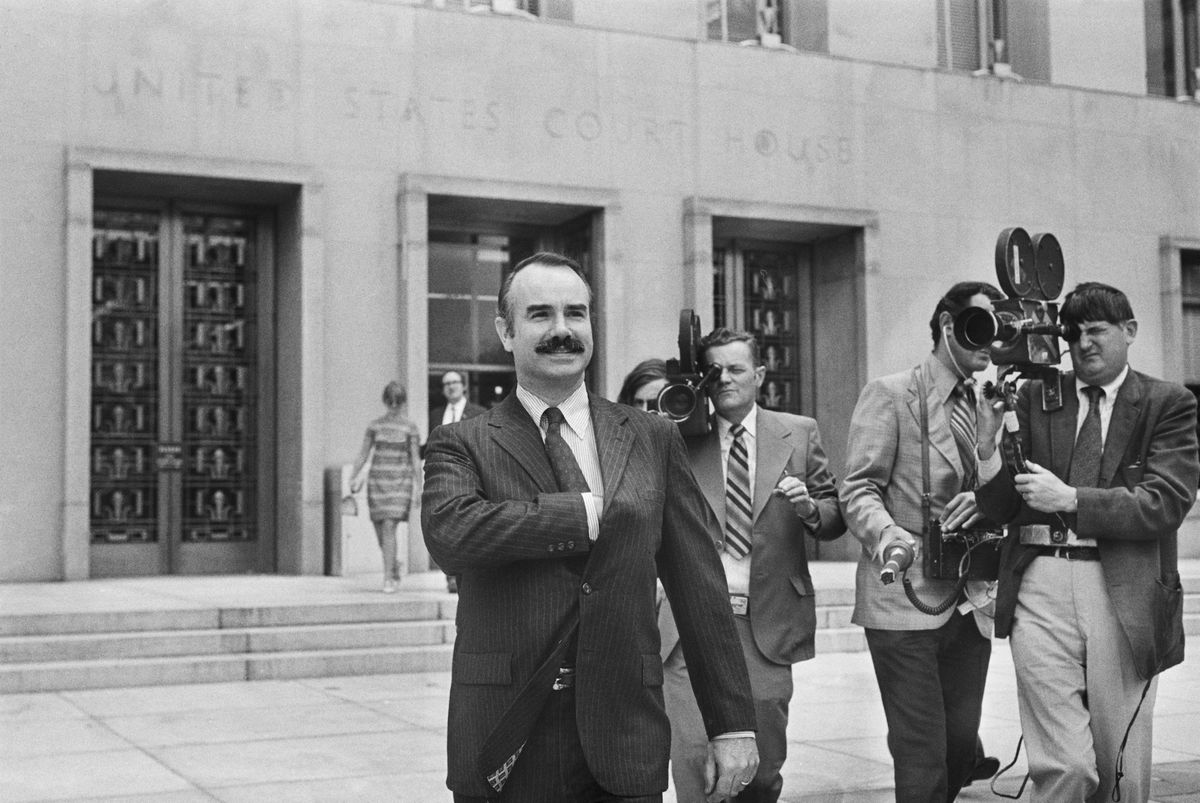 former white house aide g gordon liddy is filmed by journalists as he leaves u s district court, where he pleaded not guilty of breaking into democratic national headquarters at the watergate hotel