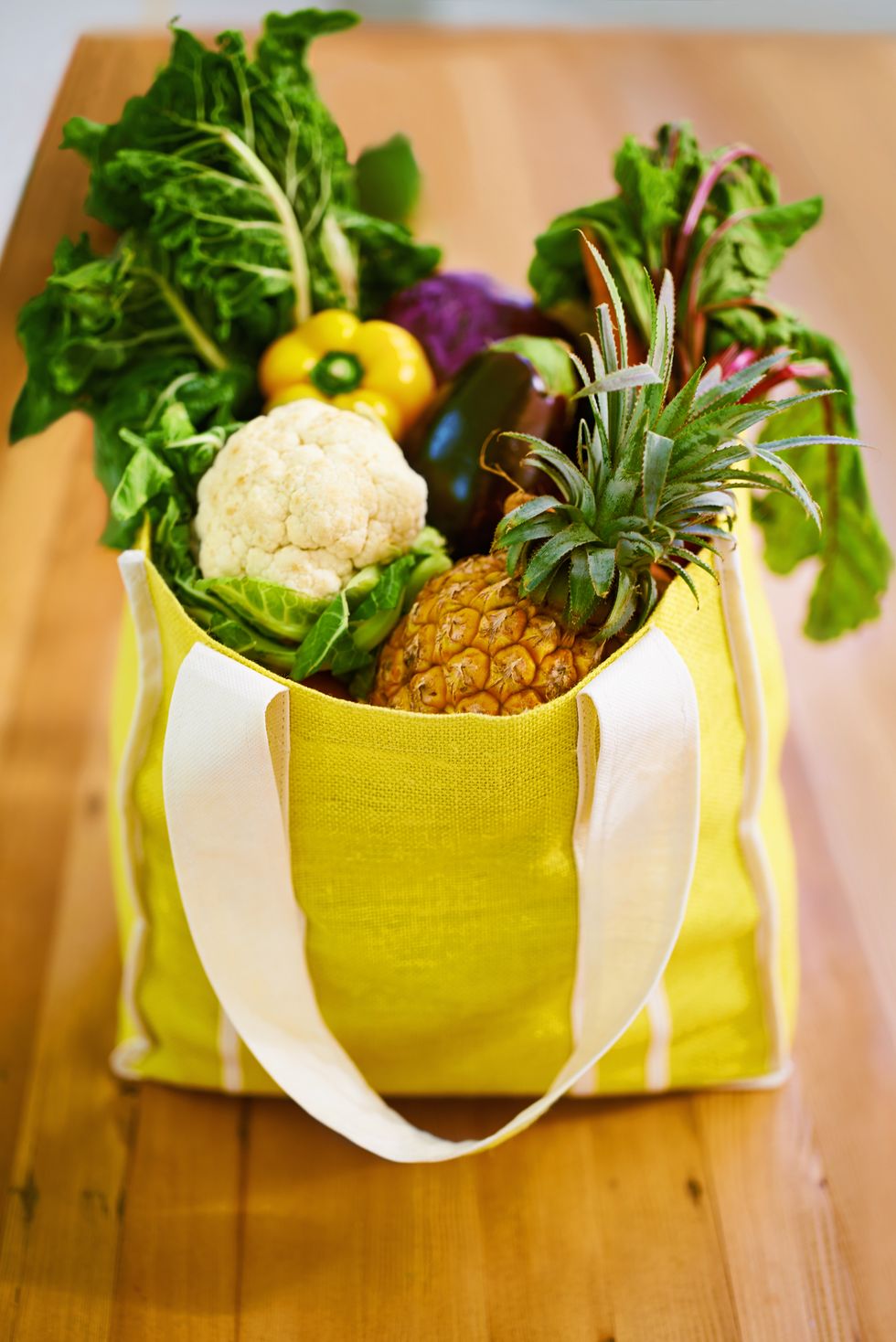 yellow reusable grocery bag filled with fruits and vegetables