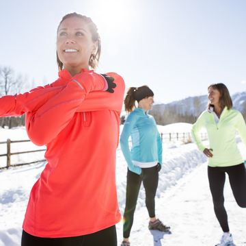 drie vrouwen doen een warming up in de sneeuw voor het hardlopen