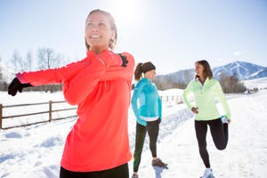 drie vrouwen doen een warming up in de sneeuw voor het hardlopen