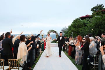 a man and woman walking down a white aisle with a crowd of people