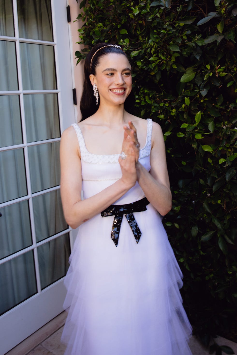 attendee in a formal dress standing by greenery