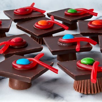 rolos and reese's cups with chocolate bars stacked on top and candy to resemble graduation caps