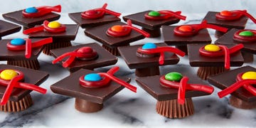 rolos and reese's cups with chocolate bars stacked on top and candy to resemble graduation caps