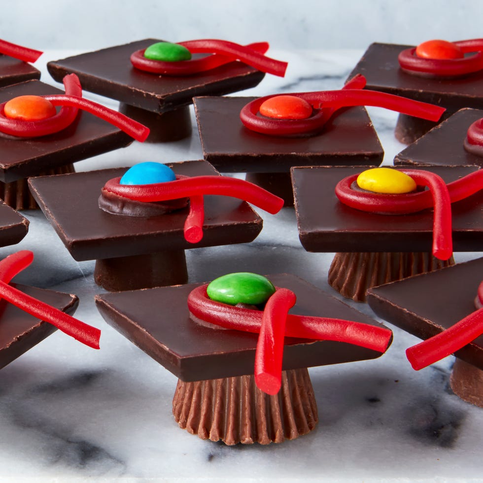 rolos and reese's cups with chocolate bars stacked on top and candy to resemble graduation caps