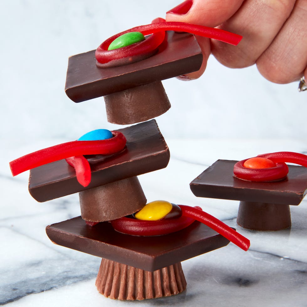 rolos and reese's cups with chocolate bars stacked on top and candy to resemble graduation caps