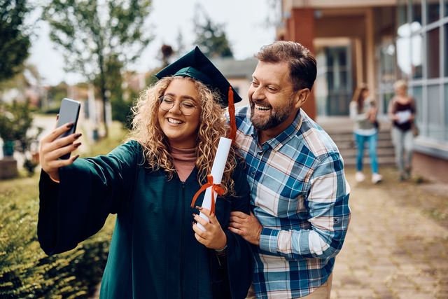 happy university graduate and her father having fun while taking selfie with smart phone