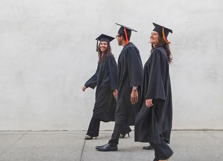 three friends walking in graduation robes and caps